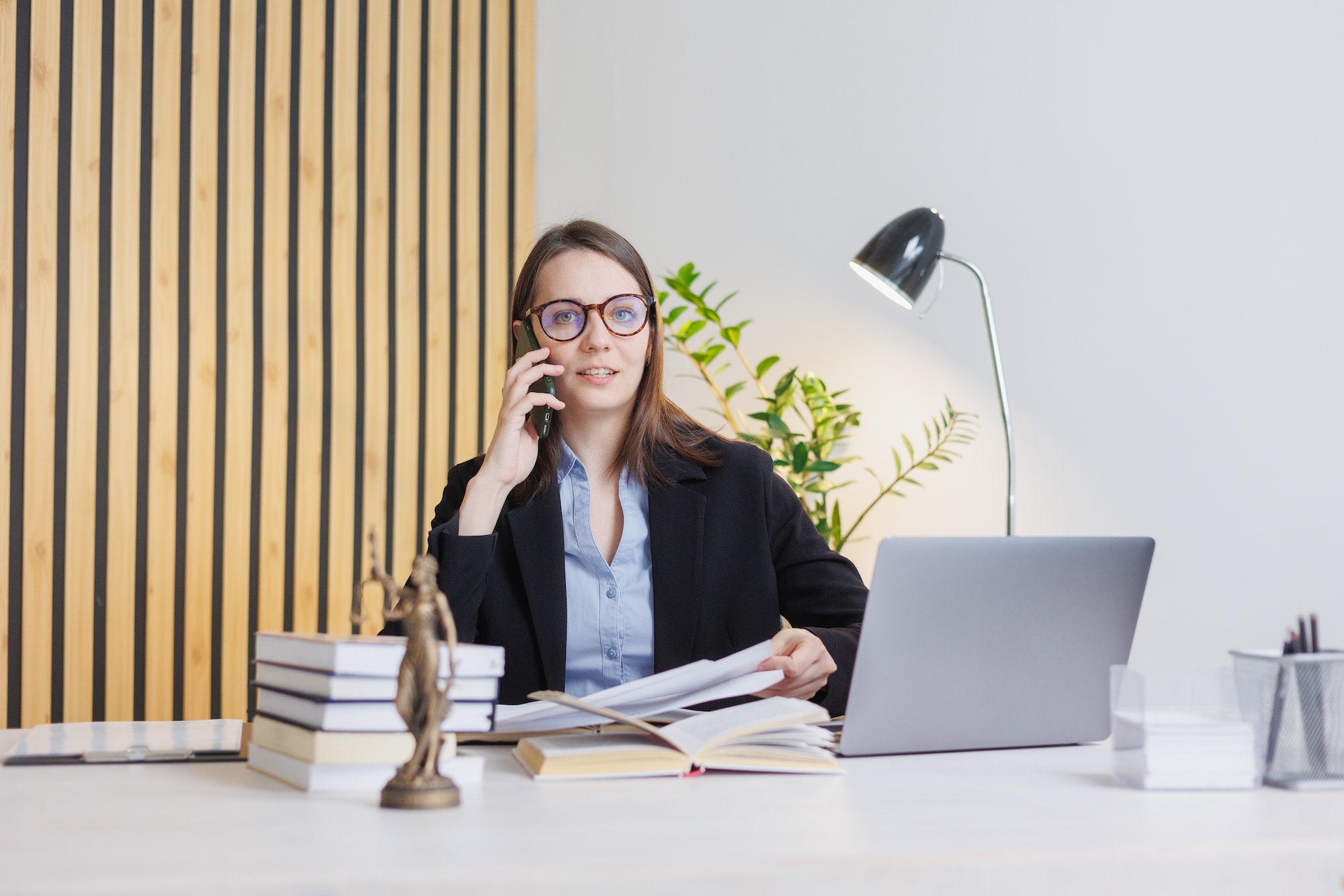 European female financier talks to clients by phone or webcam from a laptop. work in a law firm