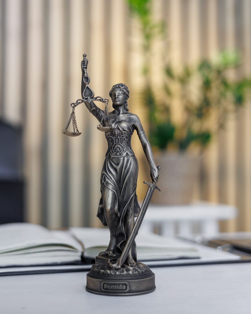 statuette of Themis, the goddess of justice, stands on a table in the office of a law firm or