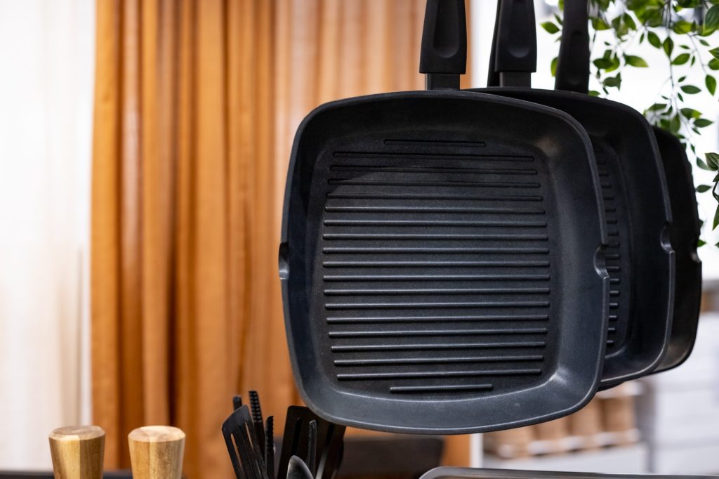 three hanging stainless frying pans for grill. Kitchen utensils.Stainless steel cookware ,