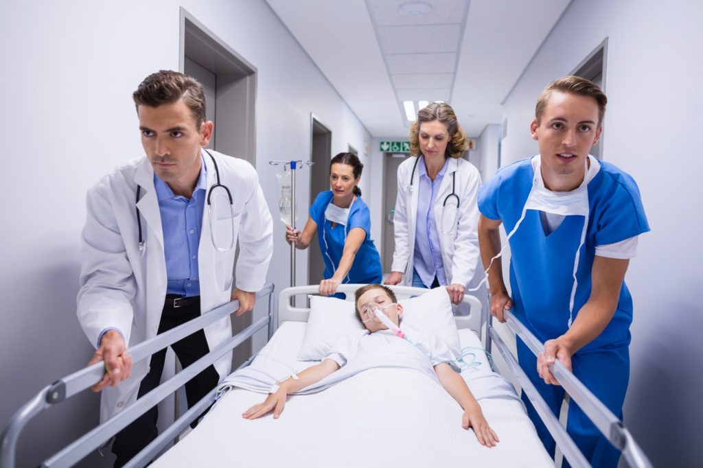 Doctors pushing emergency stretcher bed in corridor